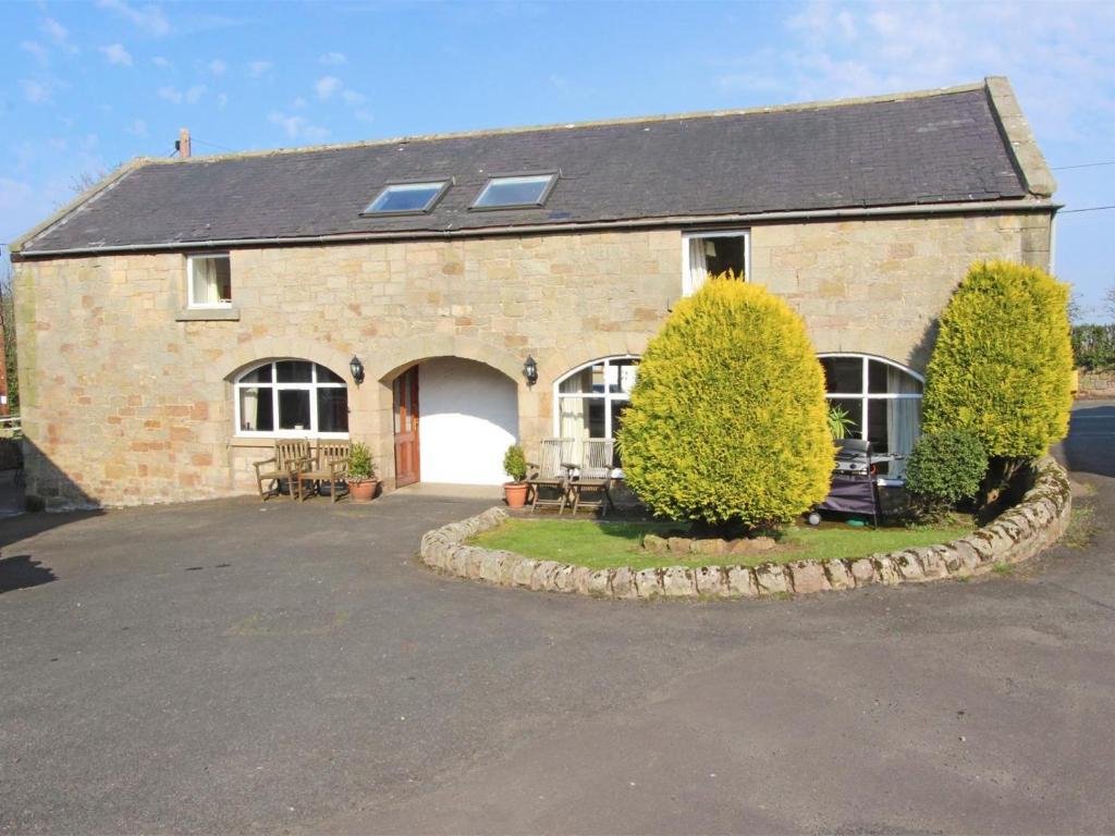 a brick house with a driveway in front of it at 3 Bed in Bamburgh oc-cn222 in Warenford