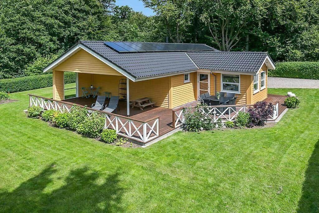a small yellow house with a deck in a yard at SJ323-Aabenraa-Kloften-14 in Loddenhøj