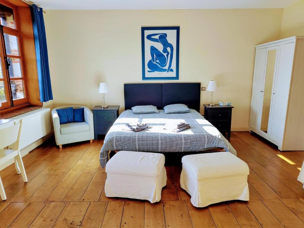 a bedroom with a bed with two white ottomans at Aubépine in Sains-du-Nord