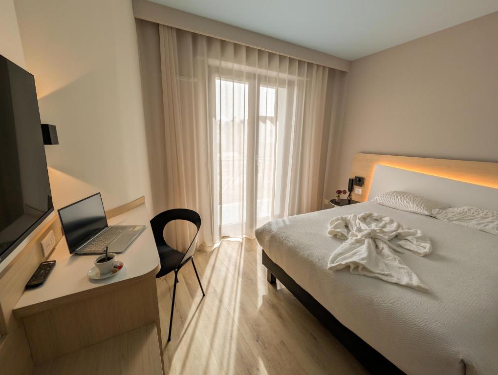 a bedroom with a bed and a desk with a laptop at Logis Hôtel Restaurant Au Lion Rouge in Bartenheim