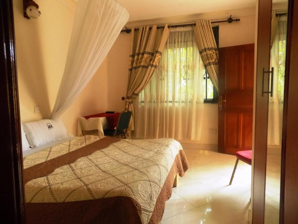 a bedroom with a bed and a chair and a window at Rhino Motel Mbarara in Mbarara