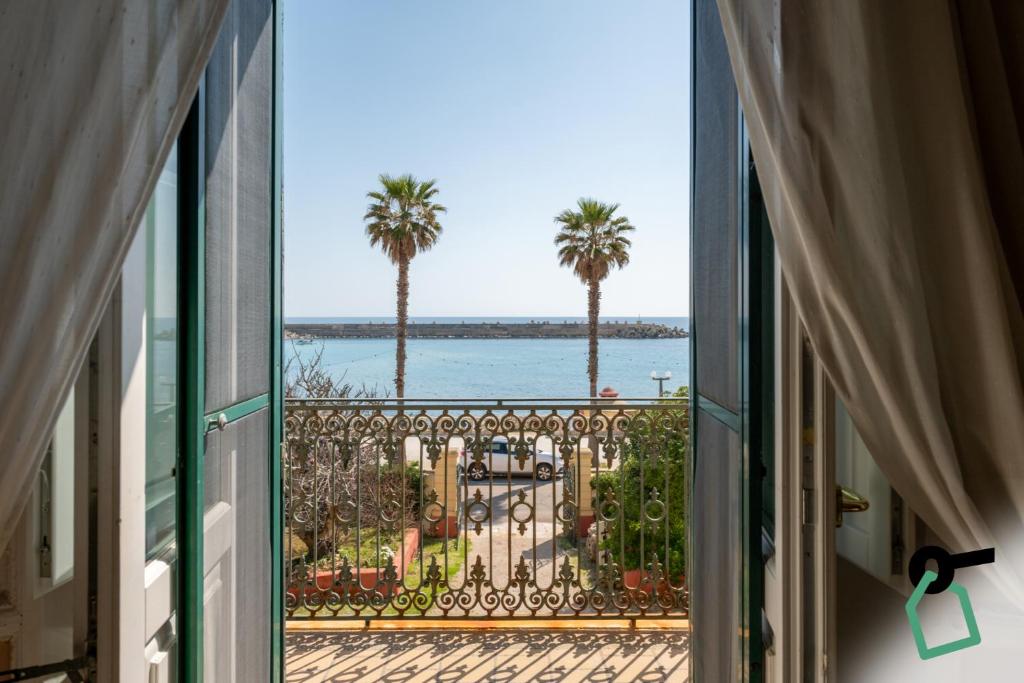 a window view of the ocean and palm trees at Hotiday Leuca Porto in Leuca