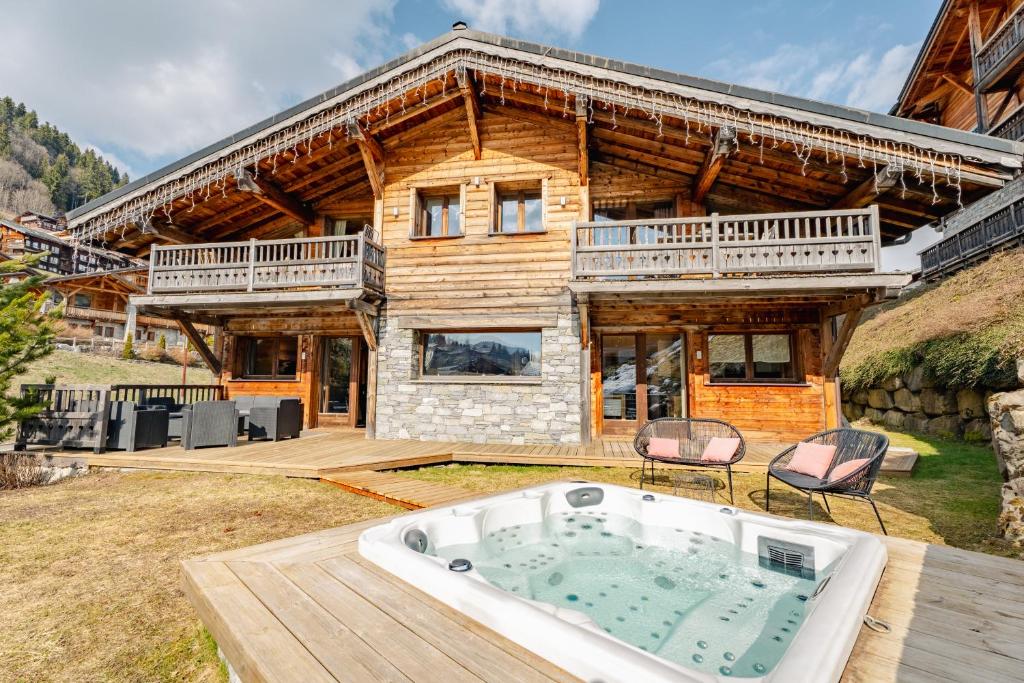 a log house with a hot tub in the yard at Hameau des clos Virolet in Les Gets