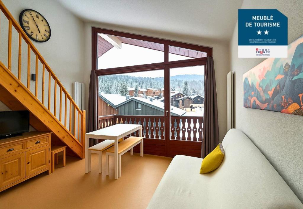 a living room with a large window and a clock at Les Eterlous N44 2P6 in Morillon