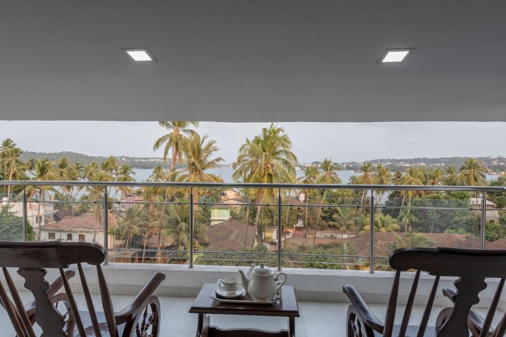 a balcony with chairs and a view of palm trees at Ocean Shores Hospitality in Candolim