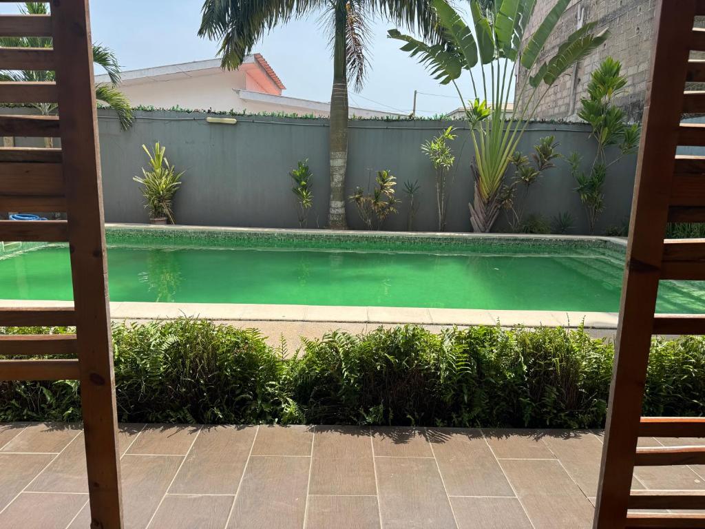 a swimming pool with green water in a backyard at CNS Guest House in Grand-Bassam