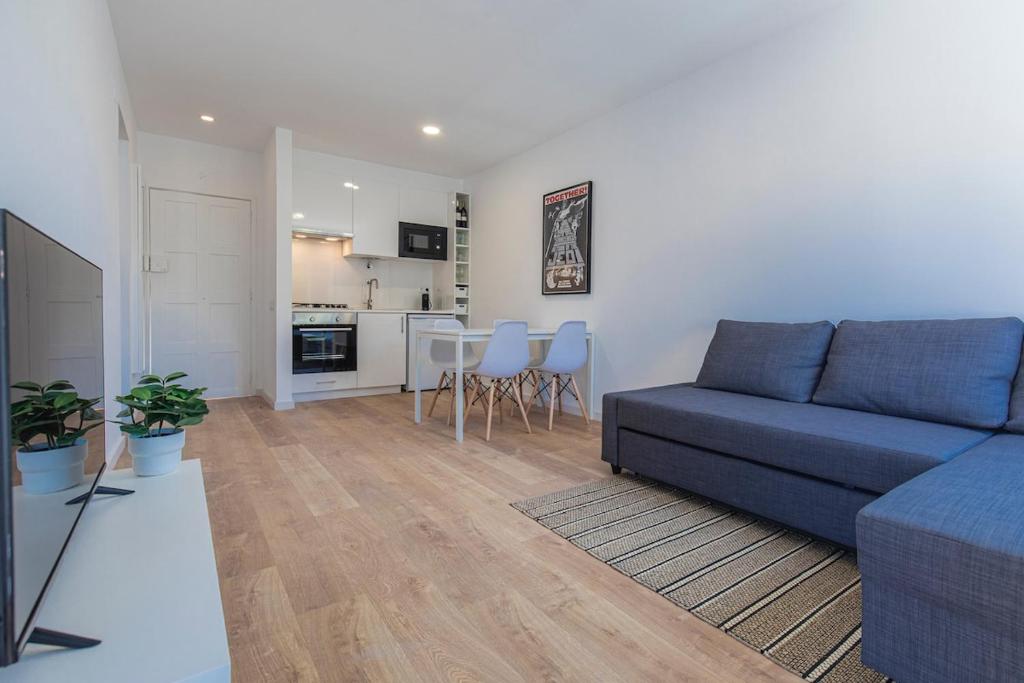 a living room with a blue couch and a kitchen at Carcavelos Village I by Staycalm in Carcavelos