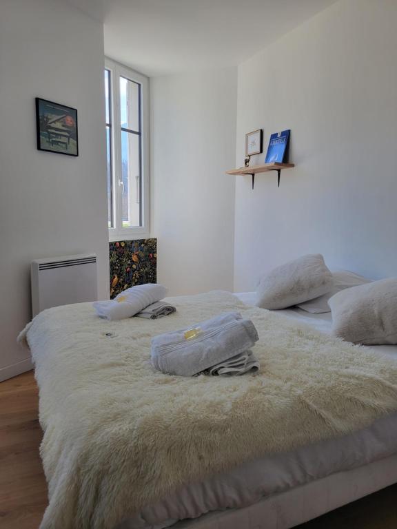 a white bedroom with two beds with towels on them at Parenthèse en Savoie in Albertville