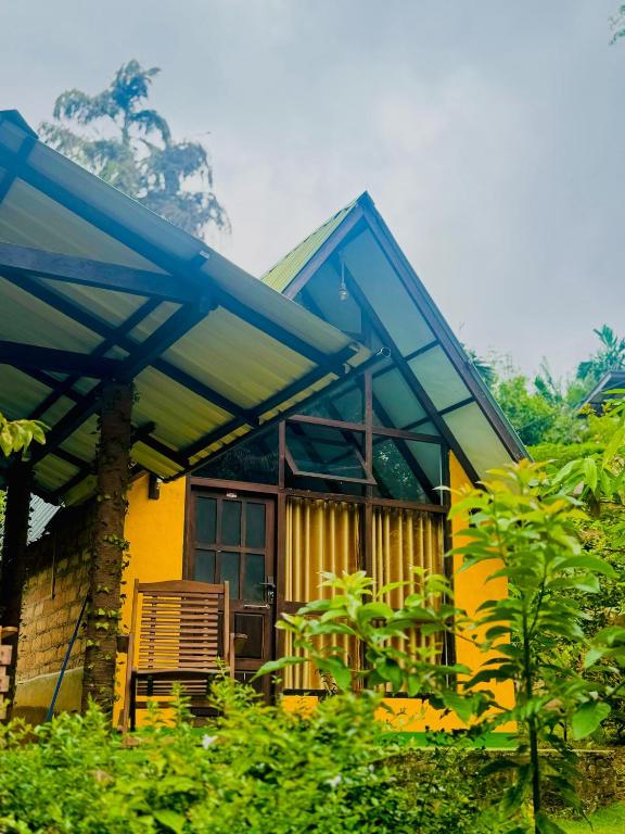 a yellow house with a blue awning at Rainforest Tea Garden Cabin-River View in Deniyaya