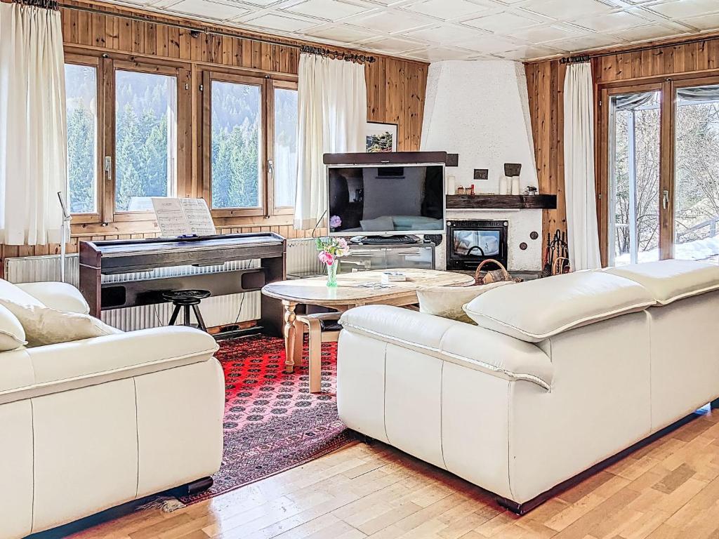 a living room with white couches and a piano at Chalet Chalet chemin du four by Interhome in Morgins