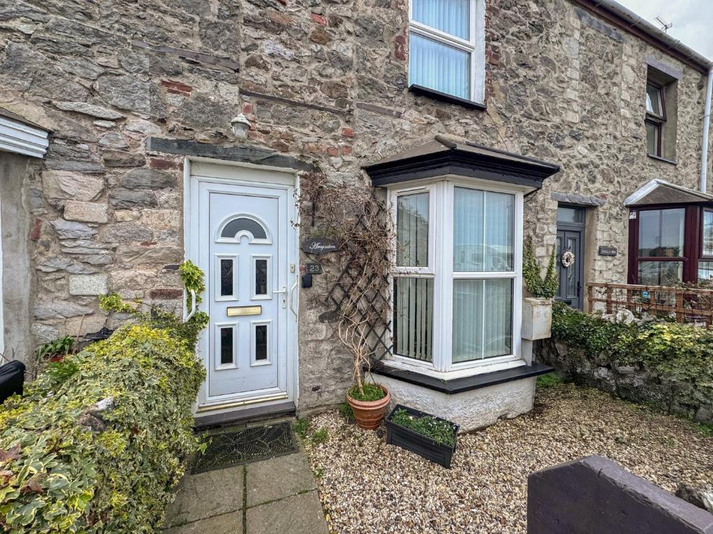 a stone house with a white door and windows at 23 Beach Road in Y Felinheli
