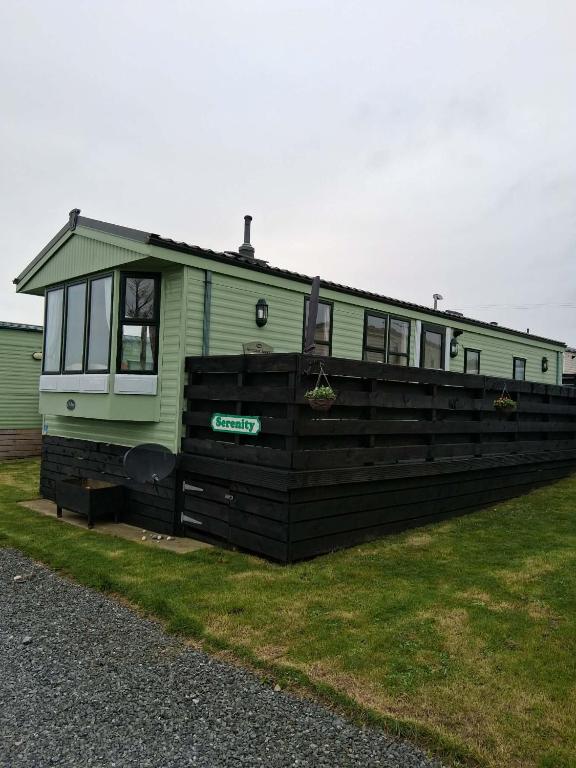 a green trailer sitting on top of a fence at Serenity in Monreith