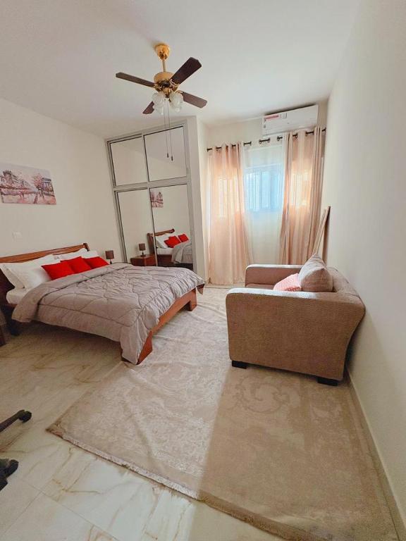 a bedroom with a bed and a couch and a ceiling fan at Residence ocean view in Ngor