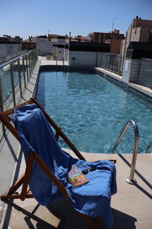 a chair sitting next to a swimming pool at Aparthotel Bcn Montjuic in Barcelona