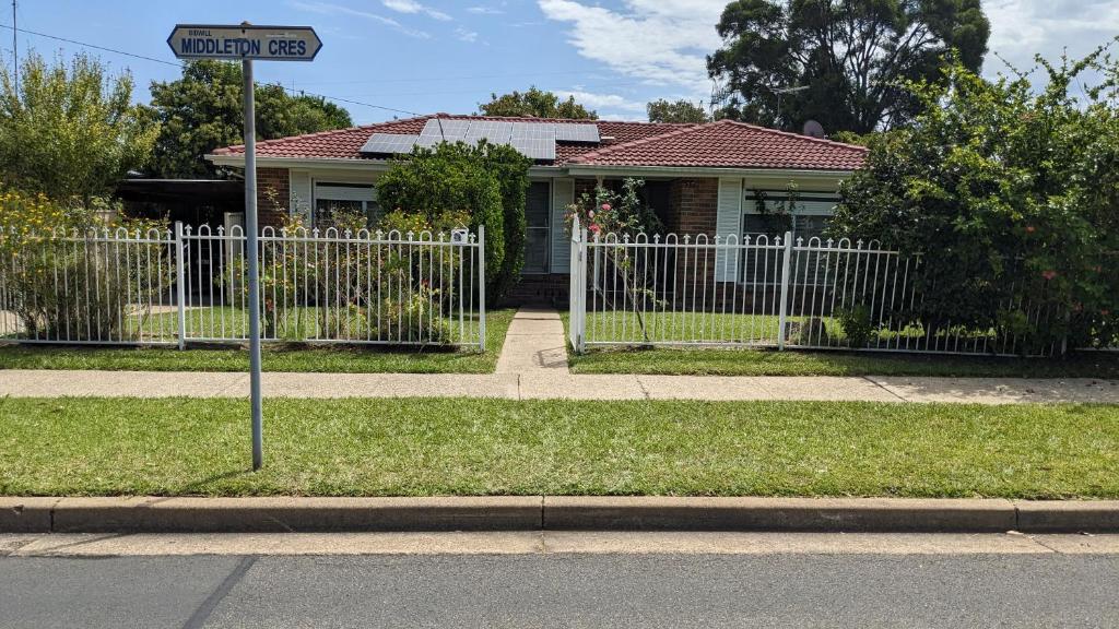 a street sign in front of a house with a fence at BIDWILL GARDENS ON MIDDLETON - 2 Rooms A Private Room with a King-Size Bed or Open Lounge Room Floor Mattress SHARED Bathroom FREE Kitchen Essentials FREE Laundry Facilities Fast WIFI HDTV NETFLIX, YOUTUBE, KAYO Meal and Transport Services Available in Bidwill
