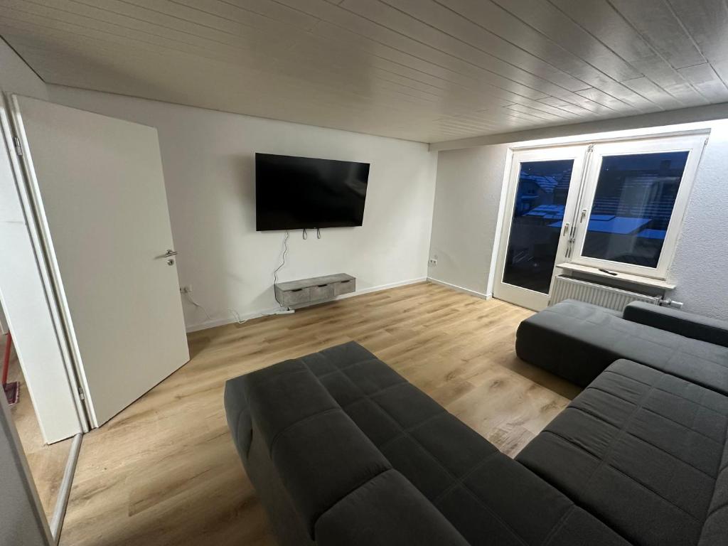 a living room with a couch and a flat screen tv at Monteurswohnung Schwarzwald in Eggingen