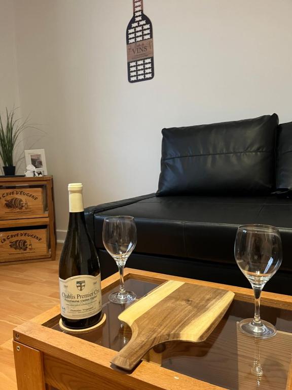 a bottle of wine and two wine glasses on a table at Studio Climatisé au centre ville in Digoin