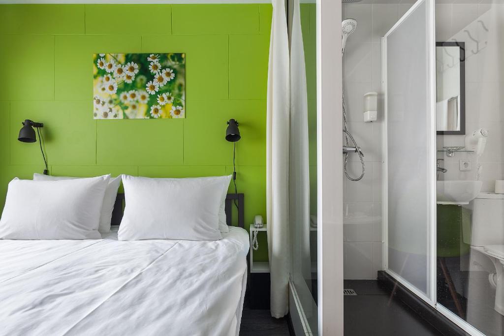Un dormitorio con una pared verde y una cama con almohadas blancas. en Live hotel by Original Hotels, en Yekaterinburg