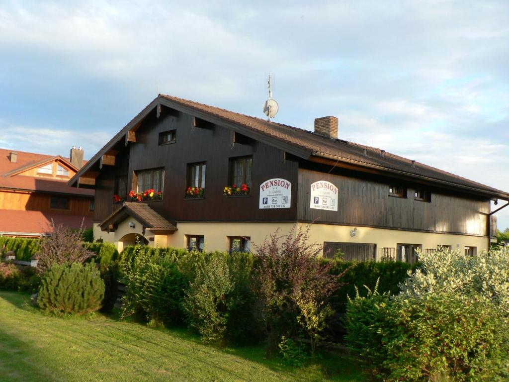 a black and white building with flowers in the windows at Penzion U Kuboňů in Volary