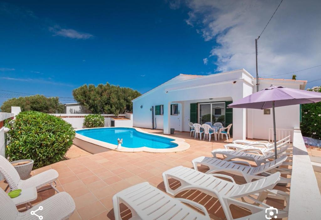 a patio with lounge chairs and a swimming pool at Villa Brehat avec piscine privée in Cala en Porter