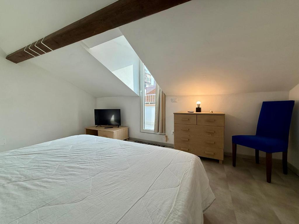 a bedroom with a white bed and a blue chair at BUDELLO Apartament in Alassio