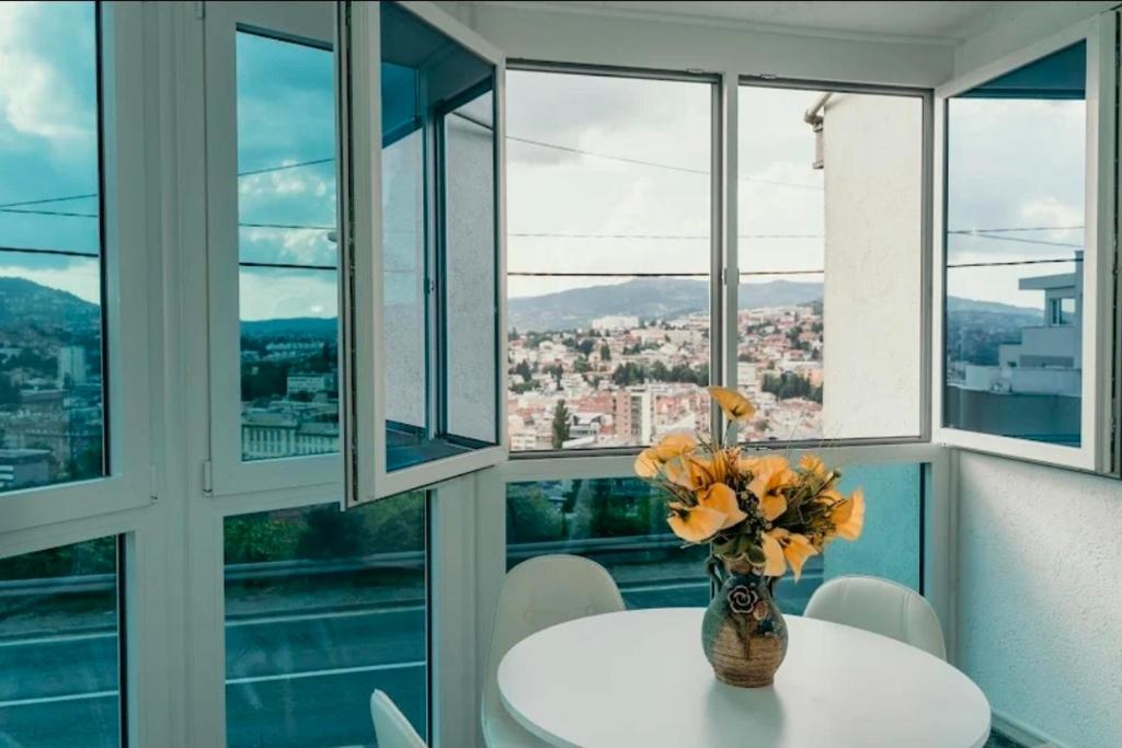 a vase of flowers on a table in a room with windows at Sarajevo Central View Apartment in Sarajevo