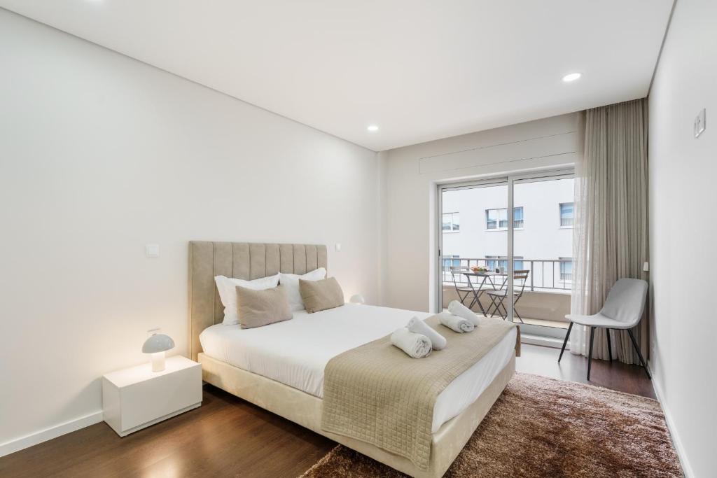 a white bedroom with a bed and a balcony at Libertà Lodge Apartment - Minho's Guest in Braga