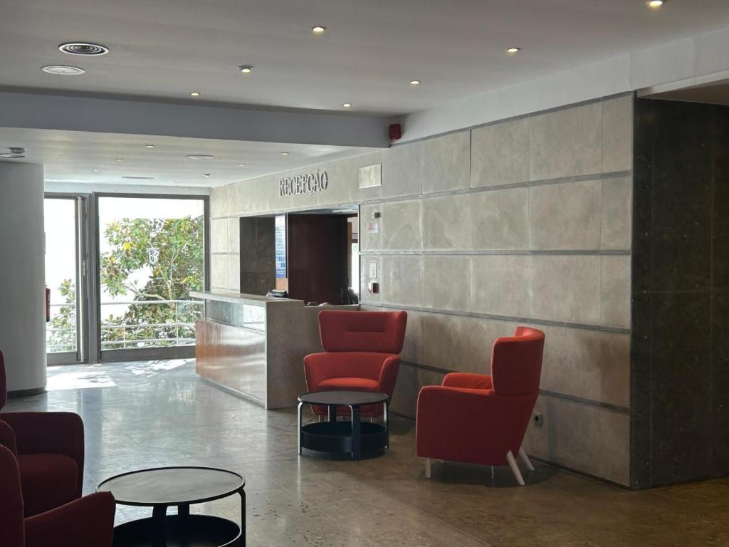 a waiting room with red chairs and a table at Flag Hotel Campo Maior in Campo Maior