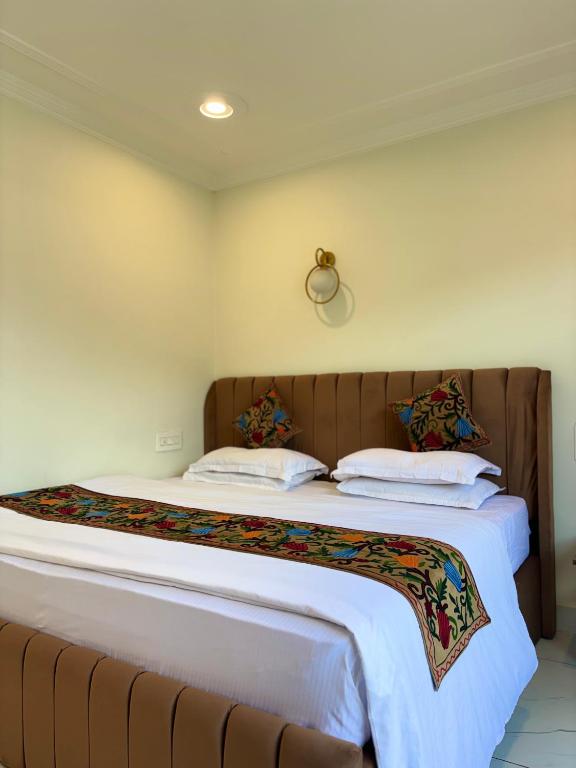 a bedroom with a large bed with white sheets and pillows at Hotel Crescent in Srinagar