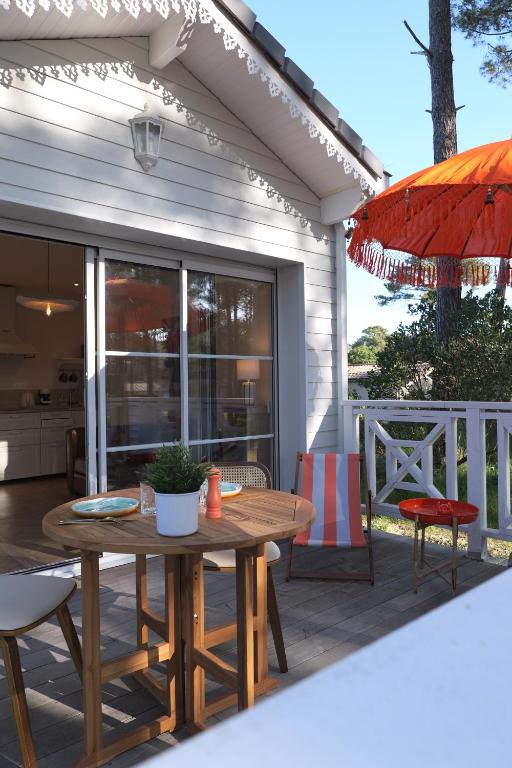 a patio with a table and chairs and an umbrella at VANILLA Lodge in Lacanau-Océan