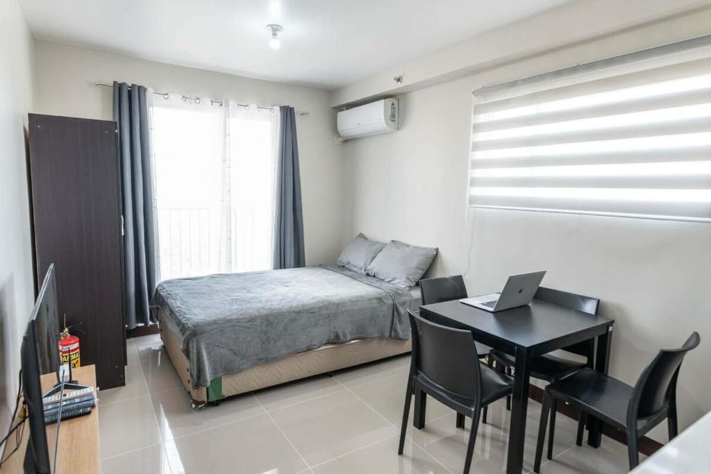 a bedroom with a bed and a desk with a laptop at Affordable Condo in Cebu with Great Views in Suba