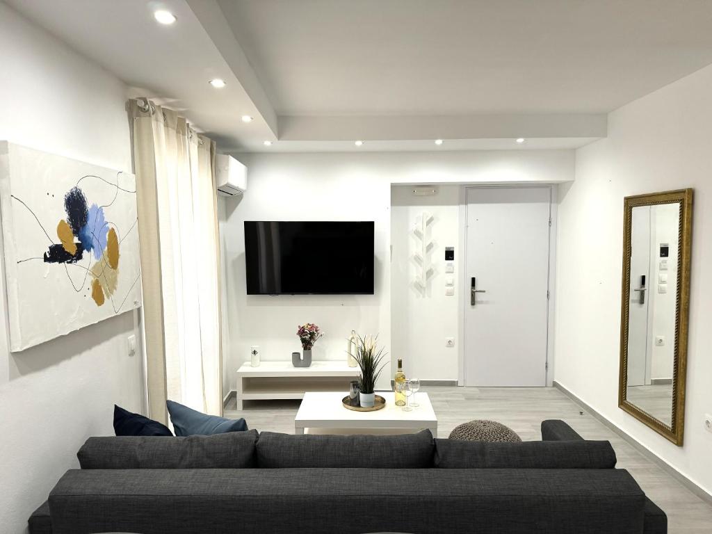 a living room with a couch and a tv at Central Suites Aegina 4 in Egina