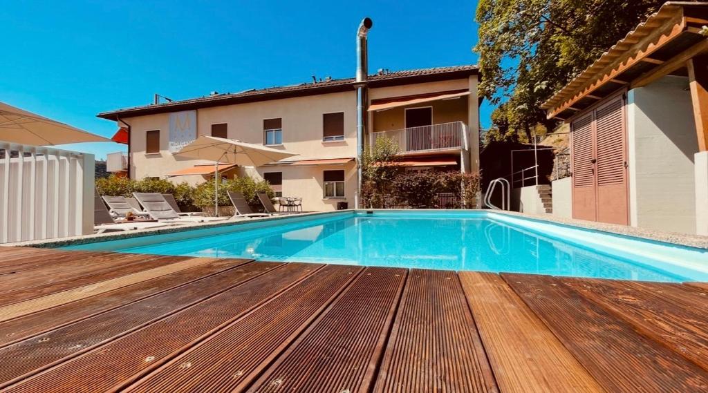 a swimming pool with a wooden deck next to a building at Albergo Morgana in Mendrisio