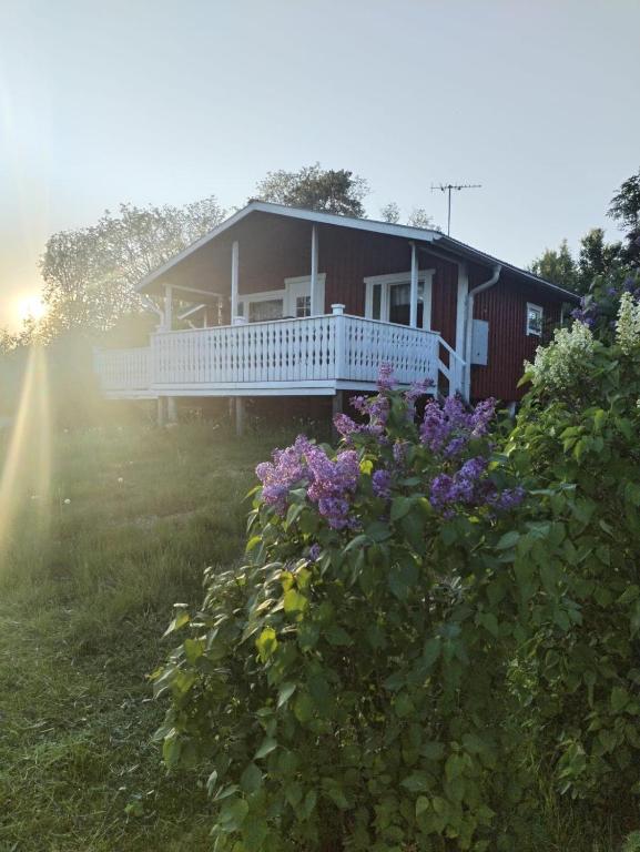 a house with a white porch and purple flowers at The red cottage in Kumlinge in Kumlinge