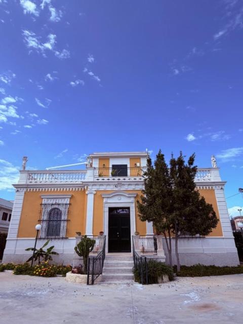 a yellow and white building with a black door at VIlla Monte D'Alba in Trani