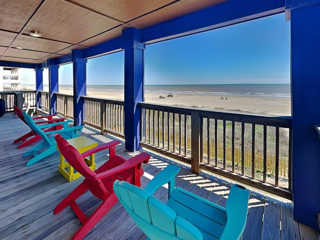 a deck with colorful chairs and the beach at Beachfront Blue in Galveston
