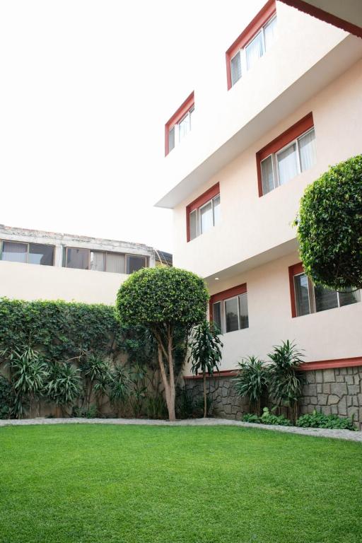 a building with a green lawn in front of it at Hotel Acámbaro Plaza in Acámbaro