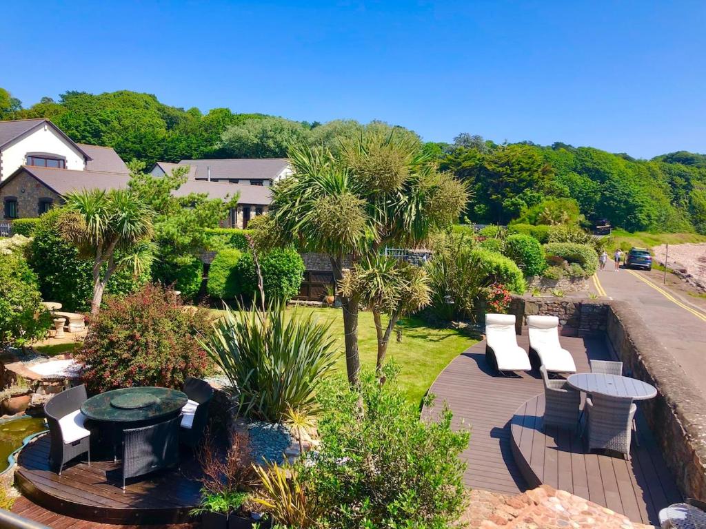 a wooden deck with chairs and a table and trees at The Beach Barn in Cardiff