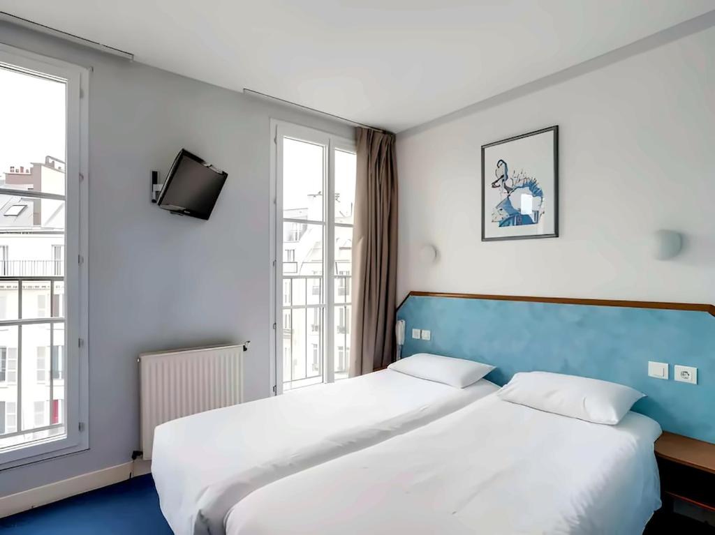 a bedroom with a large bed and two windows at Hotel Royal Mansart in Paris