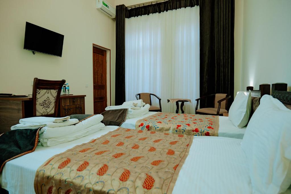 a hotel room with two beds and a television at Imperial Palace Bukhara in Bukhara