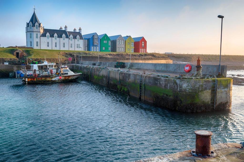 a boat is docked in the water in front of a building at Northstar - 4 Bed Luxury Apartment by Together Travel in John O Groats