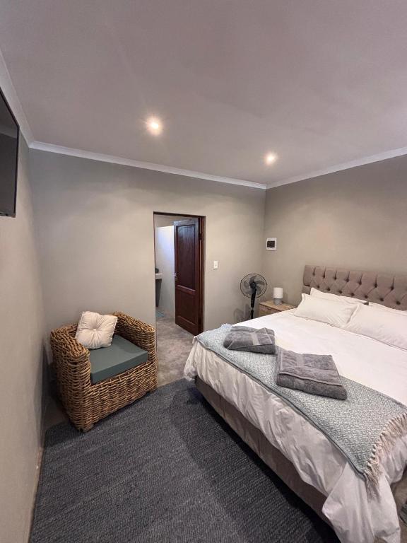 a bedroom with a large bed and a chair at LuVic Guesthouse in Naboomspruit