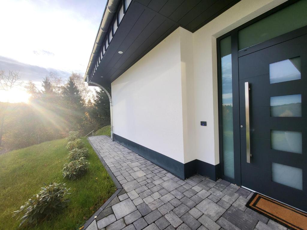 a house with a black door and a patio at Ferienwohnung Zum Adlernest in Hellenthal