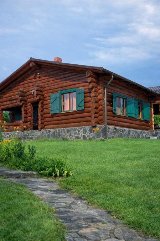 a log cabin with green windows on a green field at Blueberry Blockhouse in Hărniceşti