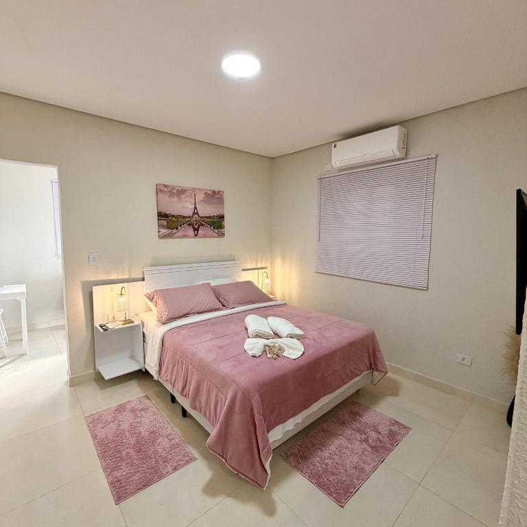 a bedroom with a large bed with a pink blanket at Chalé Rosa - Top Country Ranch in Boituva