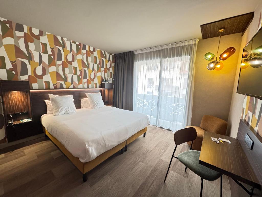 a hotel room with a bed and a desk and a window at Urban Style L'Etape in Saint-Flour