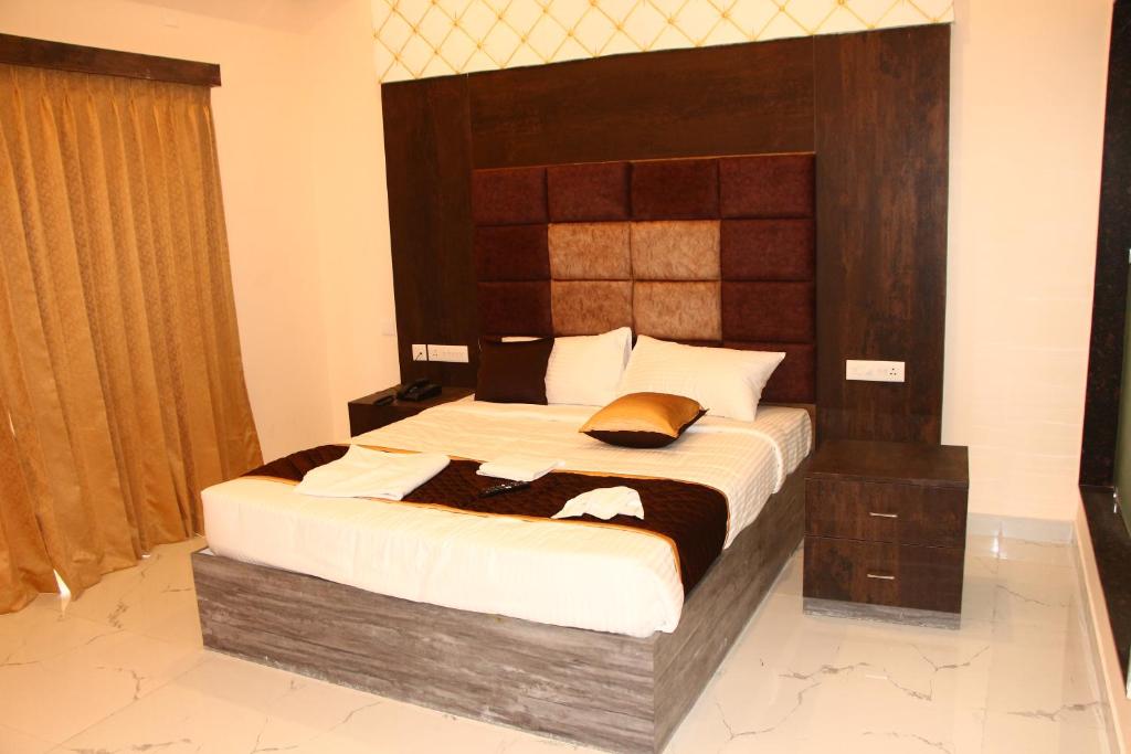 a bedroom with a large bed with a wooden headboard at sas square hotels in Tiruchirappalli
