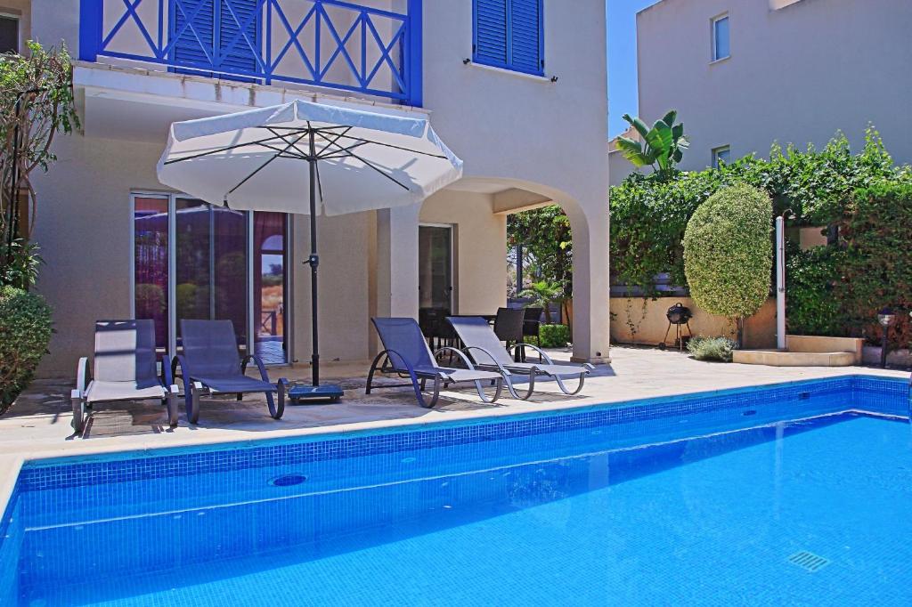 a pool with chairs and an umbrella next to a house at Villa Irina Polis in Polis Chrysochous