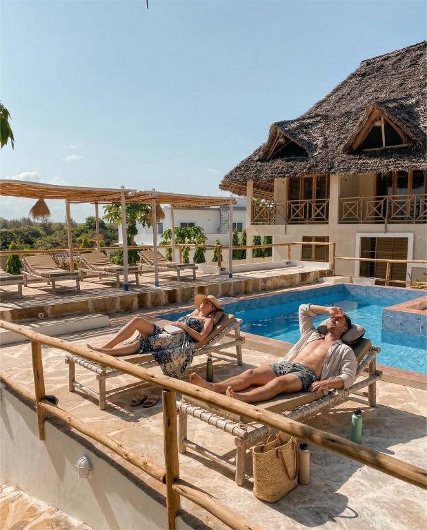three men laying on benches in a swimming pool at ZANZIBAR TROPICAL SUNSET - Adults Only Boutique Hotel by Sofia Collection in Kiwengwa