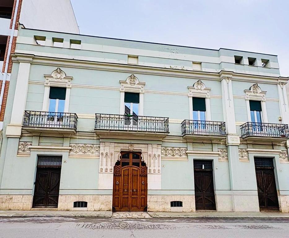 a large white building with windows and a wooden door at In Villa - Dimora Liberty in Gravina in Puglia
